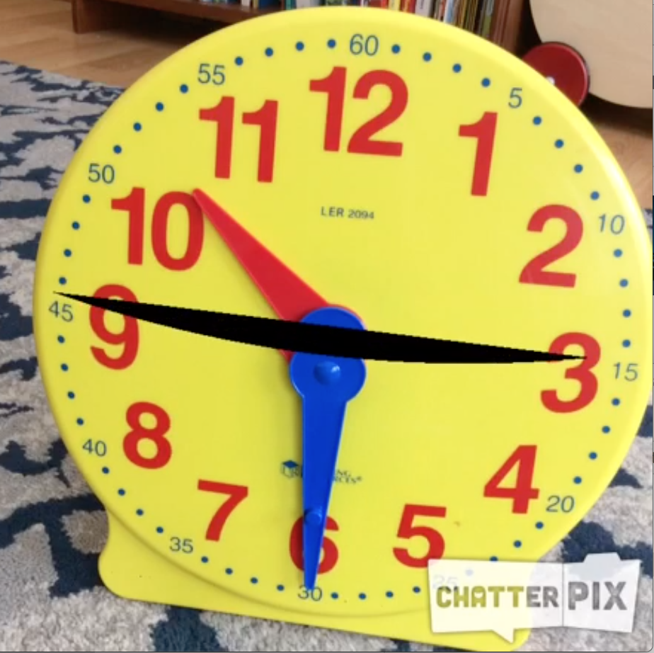 a yellow toy clock with a black line across the face; the hands of the clock point to 10:30